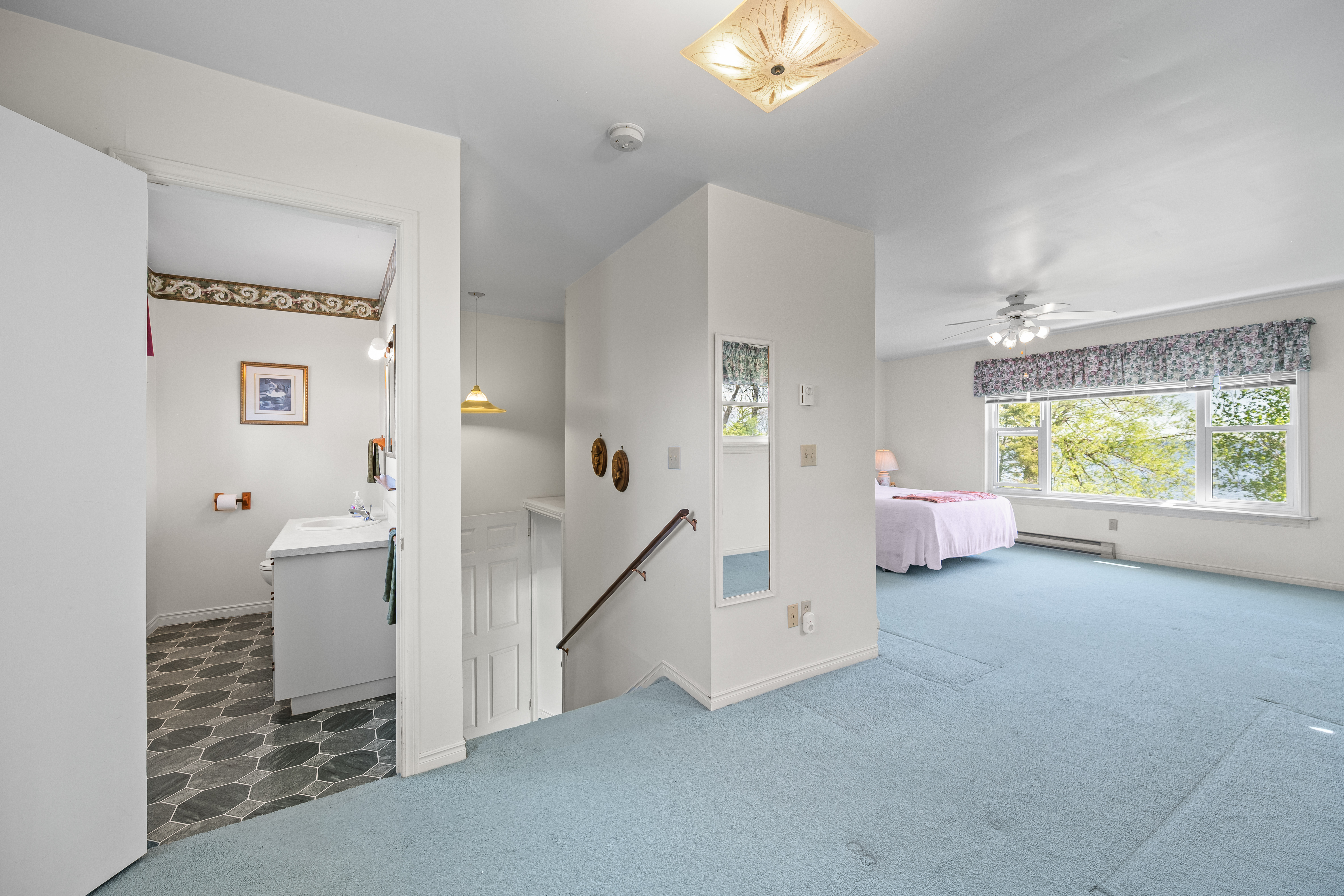 Spacious upper-level bedroom with windows framing the water